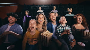 Cheerful family having fun while watching a funny movie in full cinema.